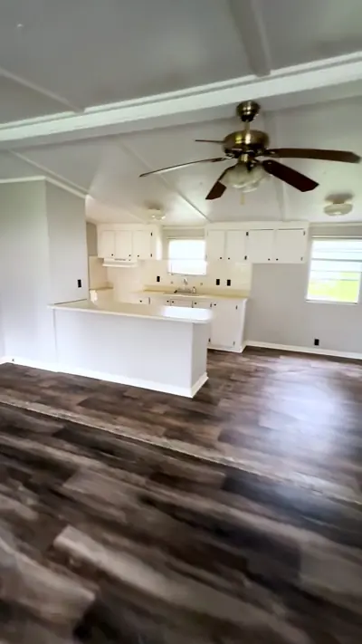 Open living room and kitchen with a ceiling fan and plank floors